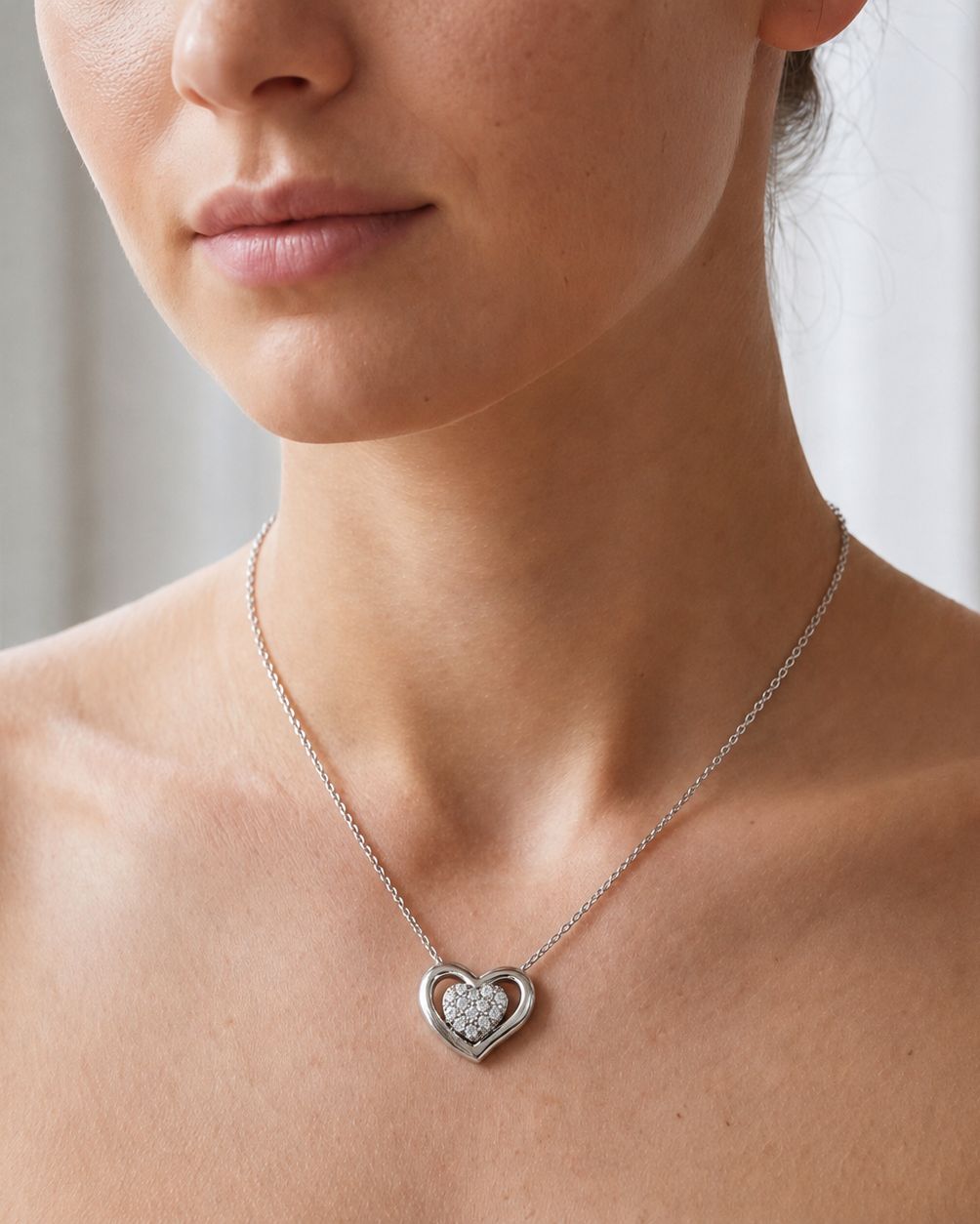 Close-up of a person wearing a silver heart-shaped necklace with a diamond pendant #color_silver