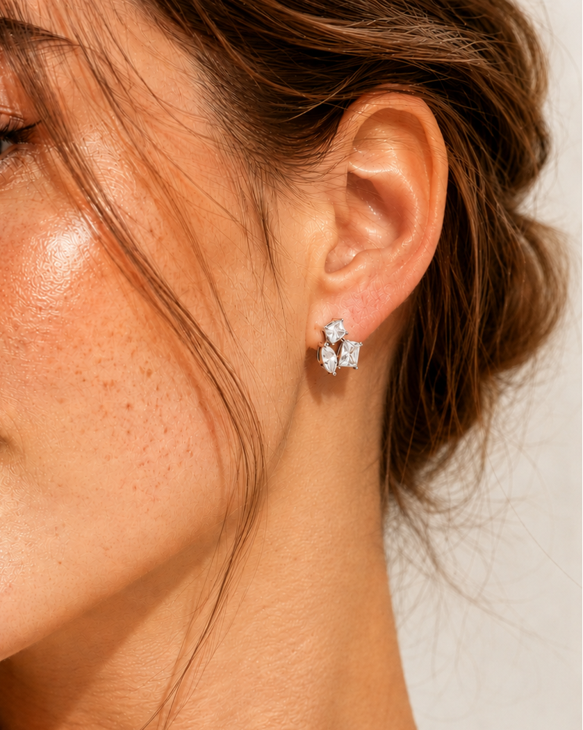 Close-up of a woman wearing a silver earring with a neutral background #color_silver