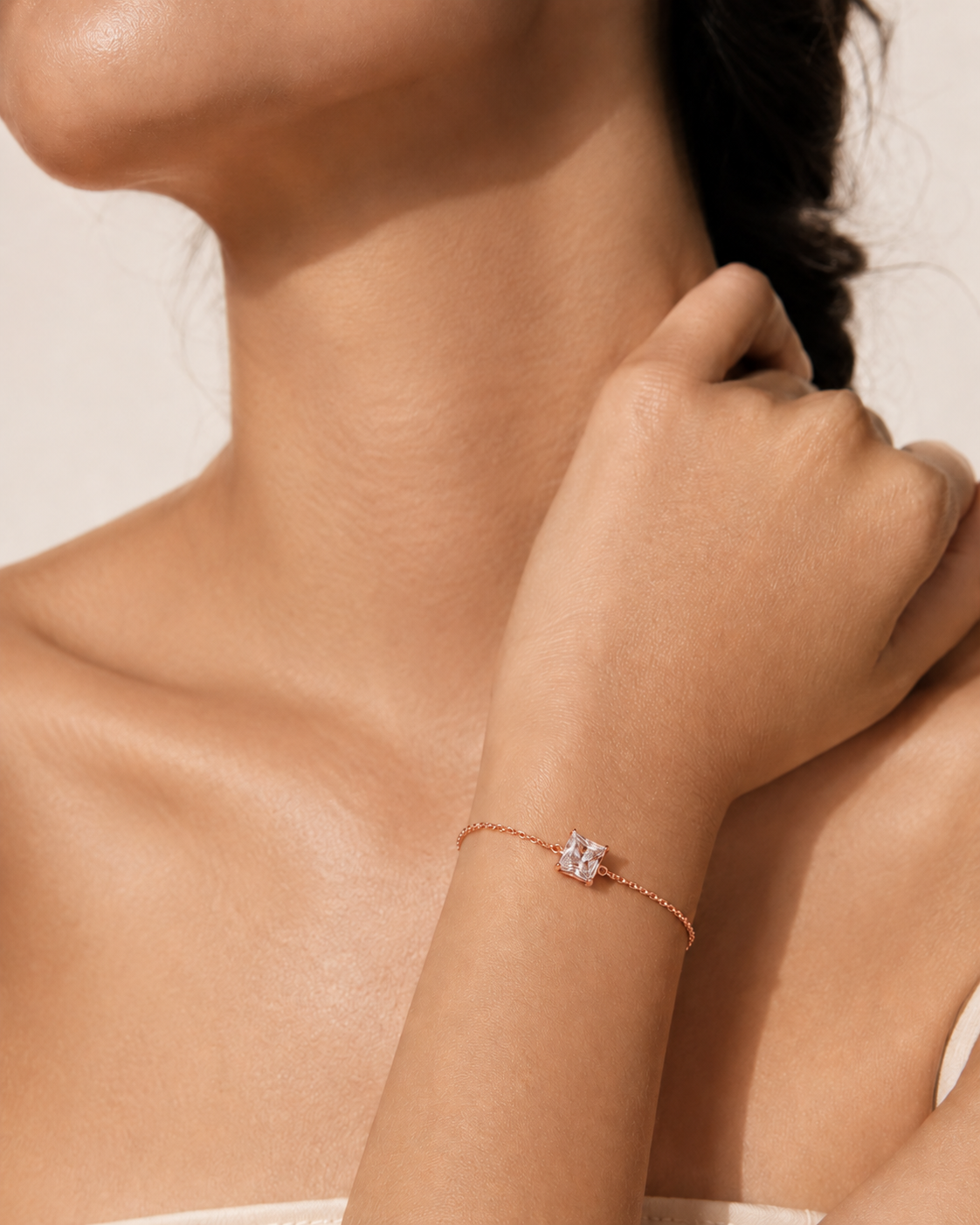 Close-up of a person wearing a delicate bracelet with a small diamond on a neutral background #colour rosegold