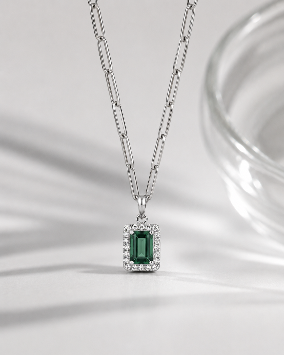 Silver necklace with a green gemstone pendant on a white fabric background