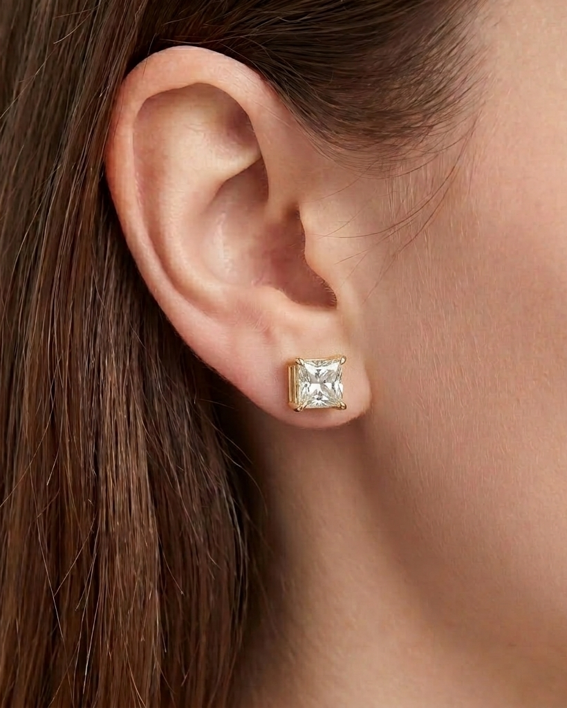 Gold earring with a clear gemstone worn by a person #color_gold
