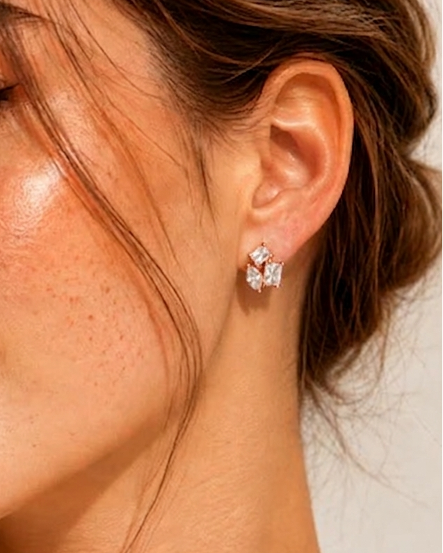 Close-up of a woman wearing diamond earrings with a neutral background #color_rose gold