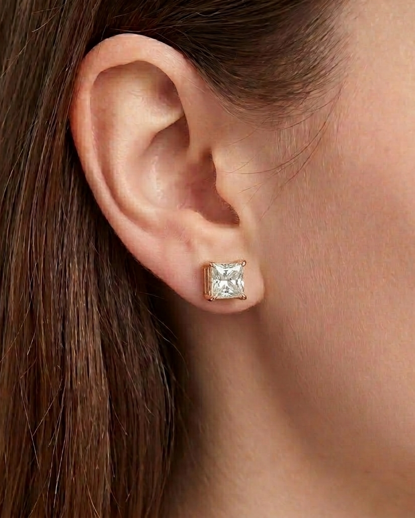 Gold earring with a clear gemstone worn by a person #color_ rose gold