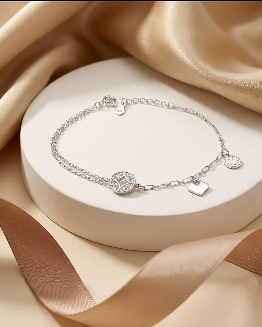 925 Sterling Silver playful charm bracelet with circle, square, and smiley charms.