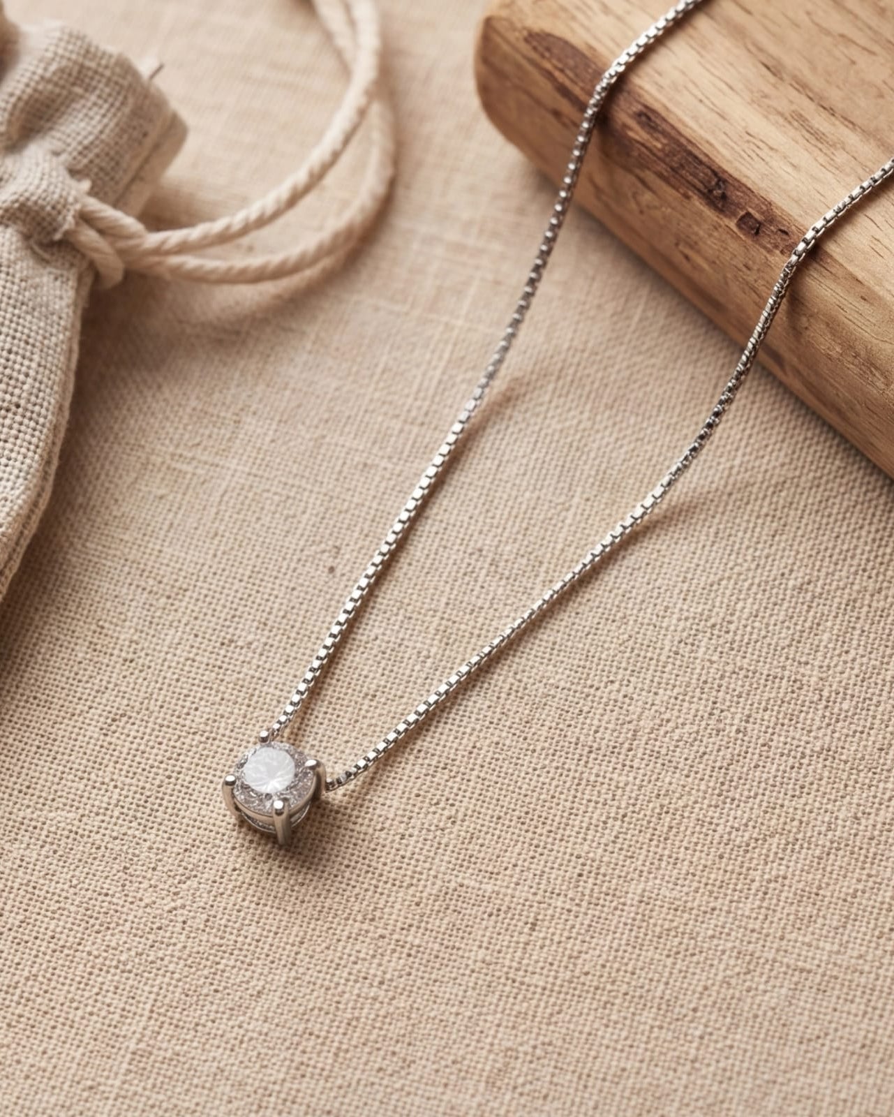 Silver necklace with a pendant on a beige fabric background #color_silver