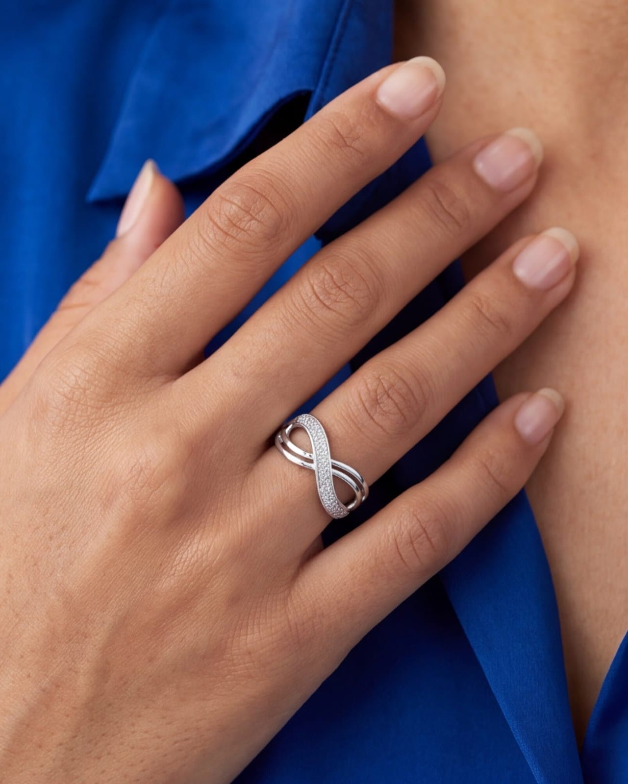 Hand wearing a silver ring with a blue background #color_silver