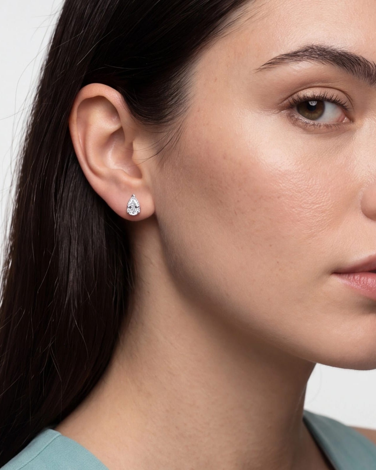 Close-up of a woman wearing a diamond earring against a neutral background #color_silver