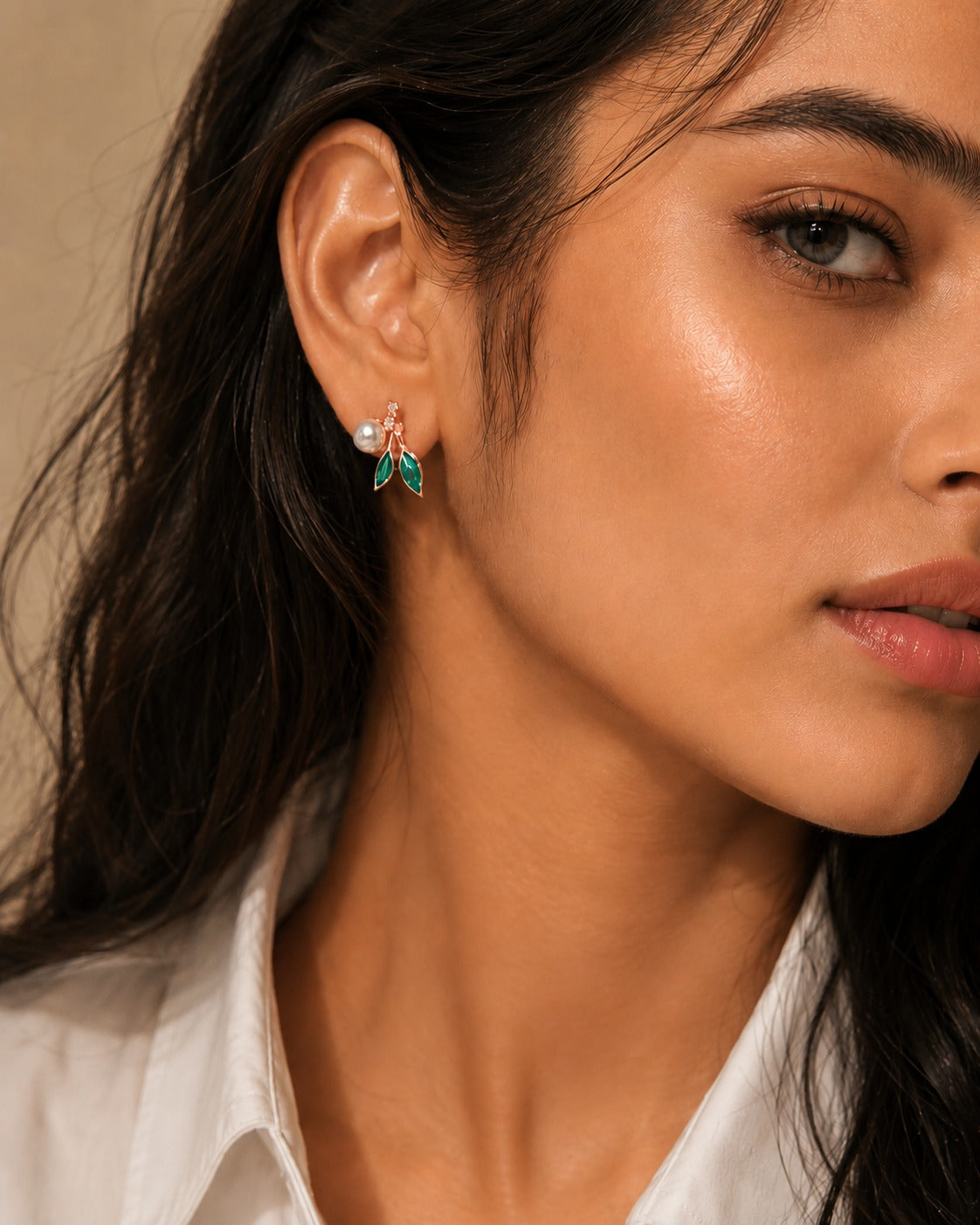 Close-up of a woman wearing earrings with a neutral background #color_rose gold