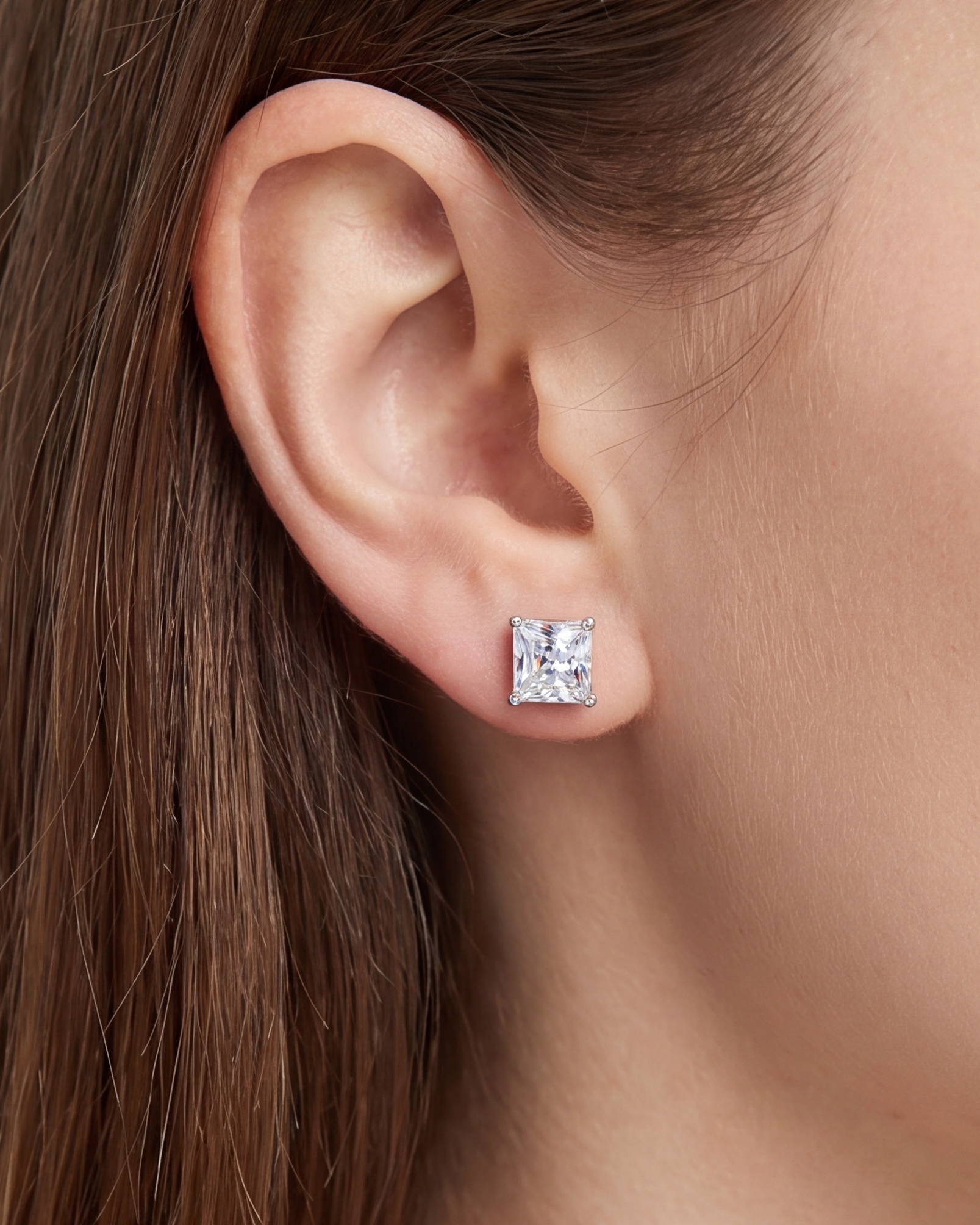 Close-up of an ear wearing a square-cut diamond earring #color_silver