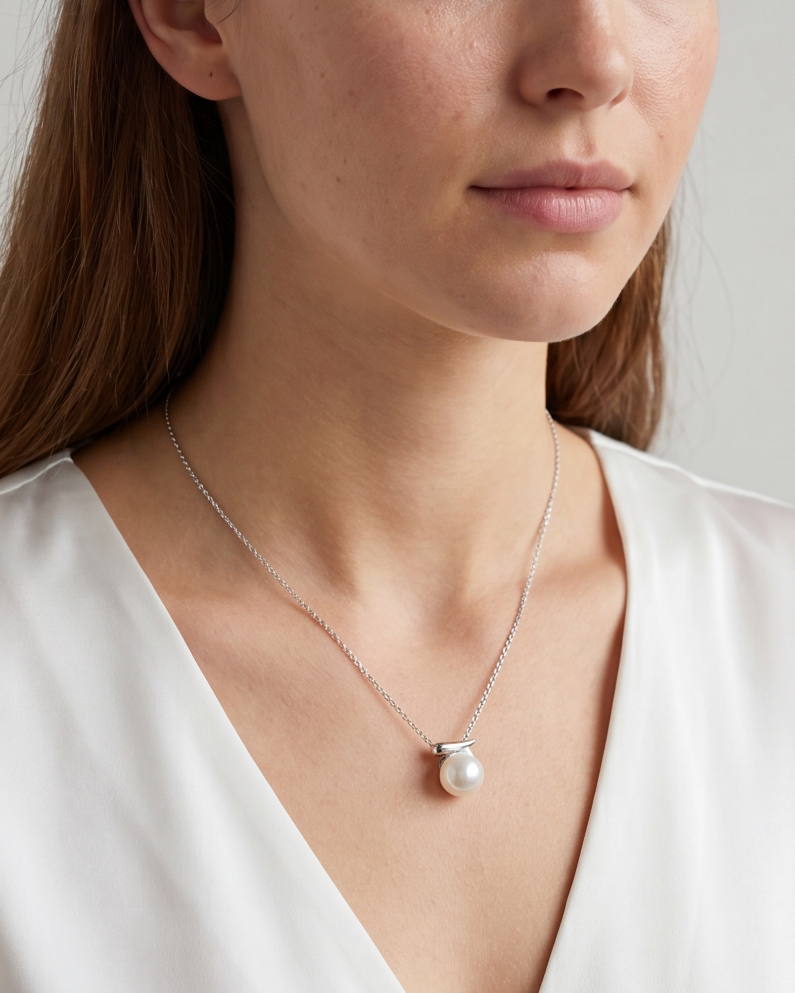Woman wearing a pearl necklace against a neutral background #color_silver