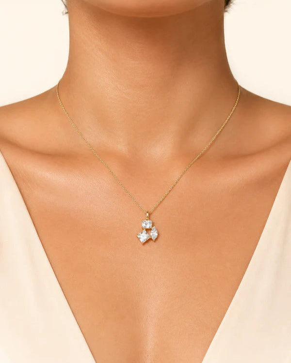 Gold necklace with a star-shaped pendant on a model wearing a beige top #color_gold