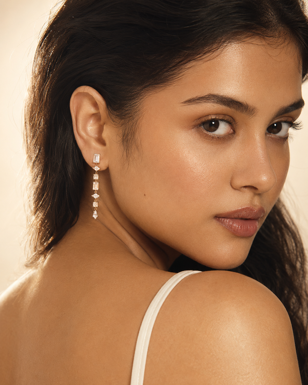 Woman wearing a diamond earring with a neutral background #color_gold