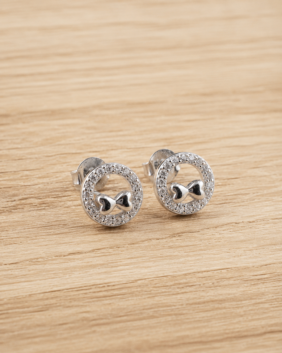 round stud earrings with bow motif and sparkling pavé border #color_silver