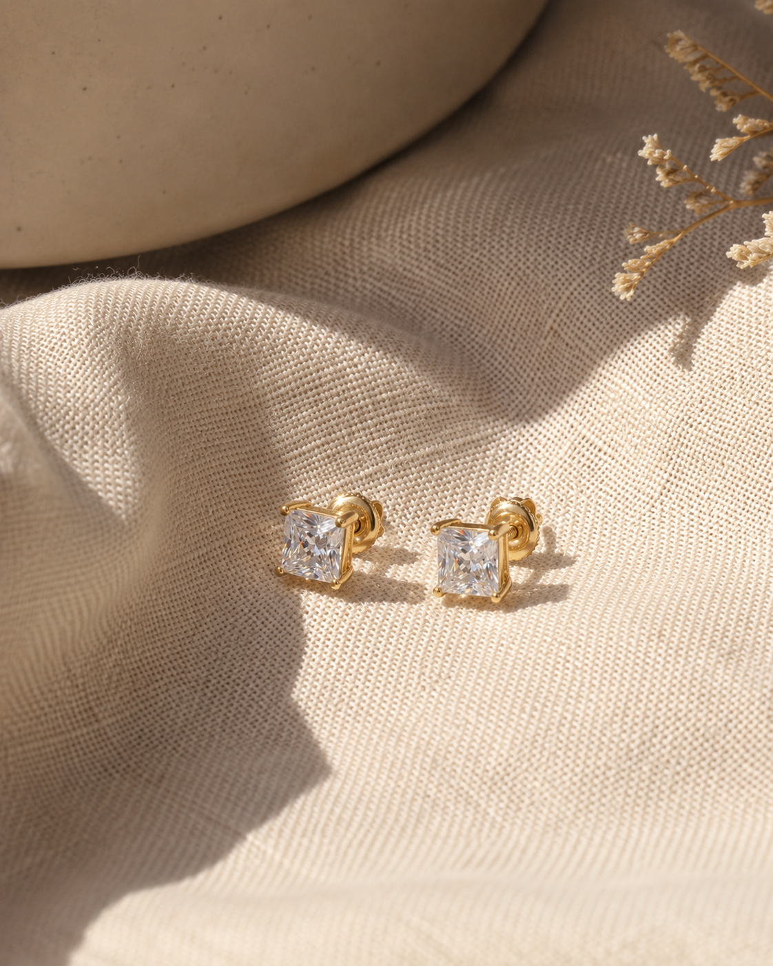 Gold earring with a clear gemstone worn by a person #color_gold