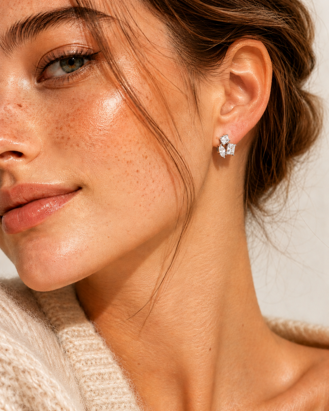 Close-up of a woman wearing a silver earring with a neutral background #color_silver