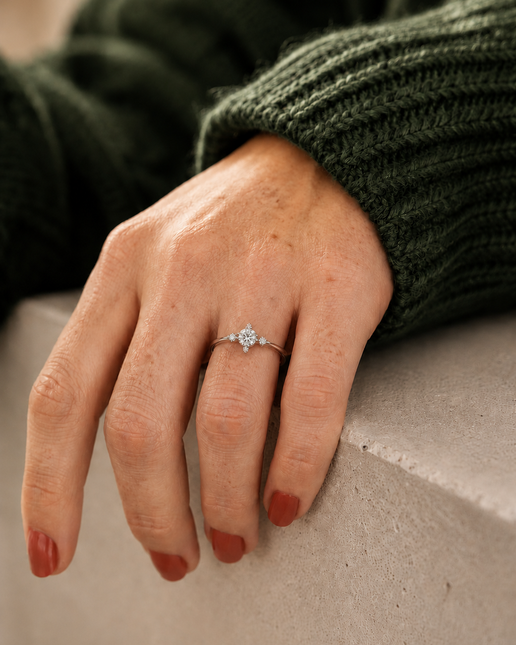 Hand wearing a ring with a green sweater and beige surface #colour rose gold