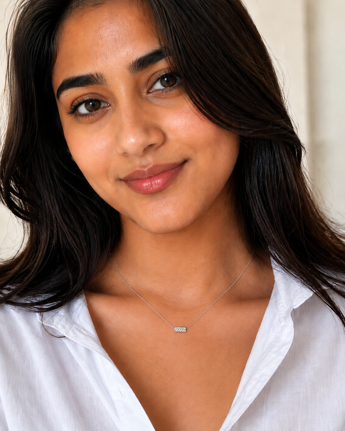 Woman wearing a white shirt with a necklace against a neutral background #color_silver