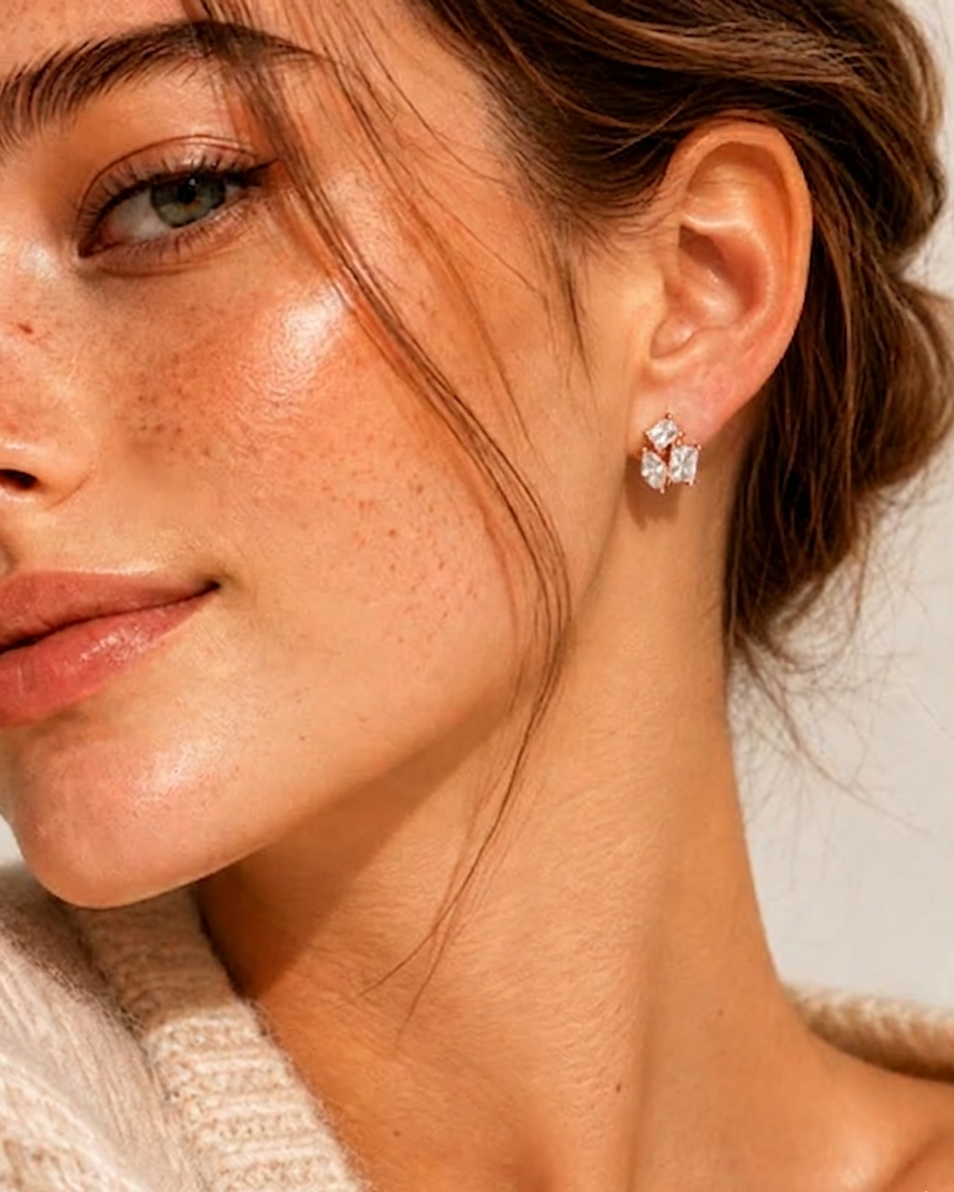 Close-up of a woman wearing diamond earrings with a neutral background #color_rose gold