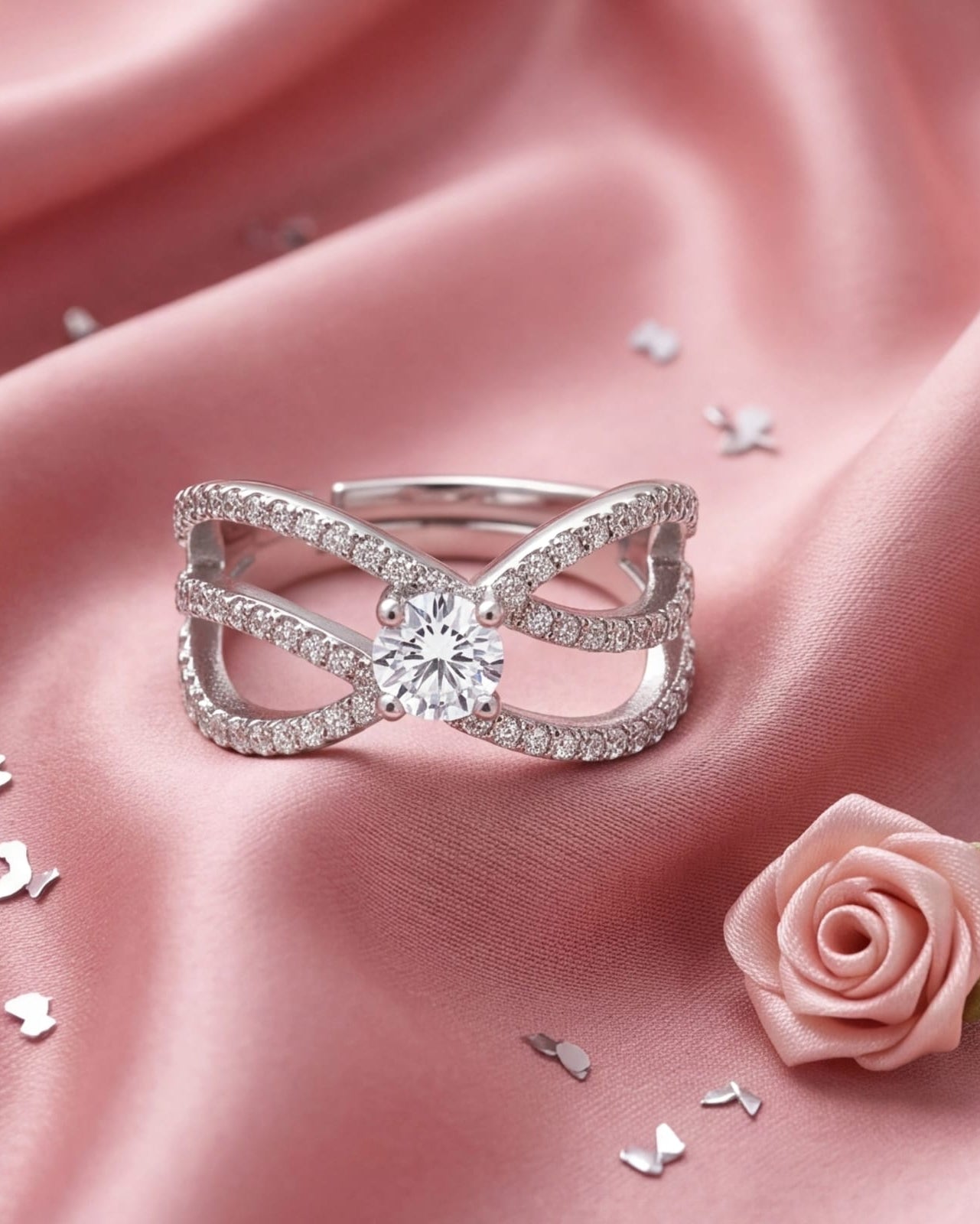 Silver ring with a diamond on a pink satin background with a rose and feathers. #color_silver