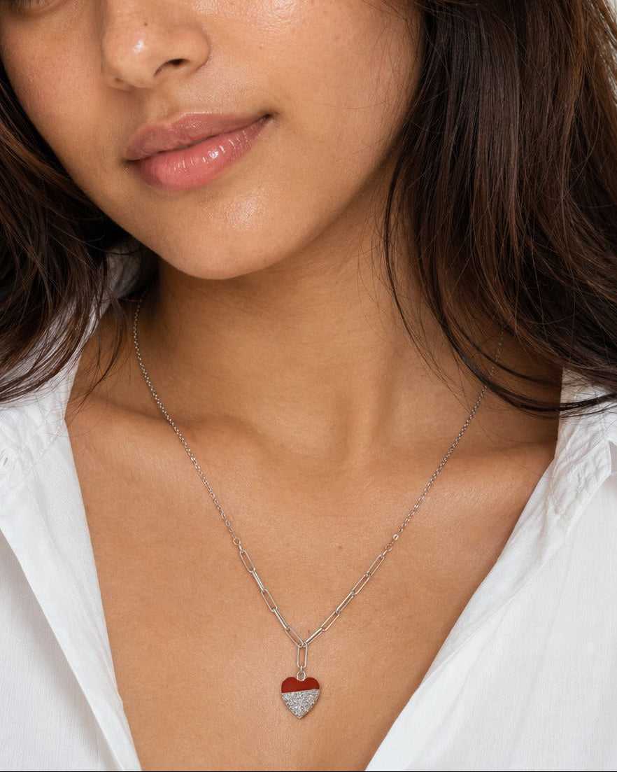 Woman wearing a necklace with a heart pendant against a neutral background #color_silver