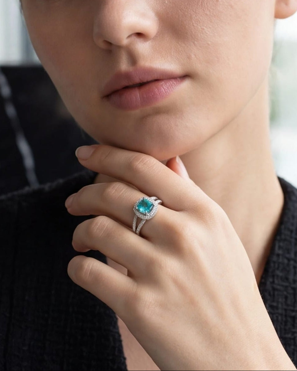 Woman wearing a ring with a blue gemstone, indoors. #color_silver