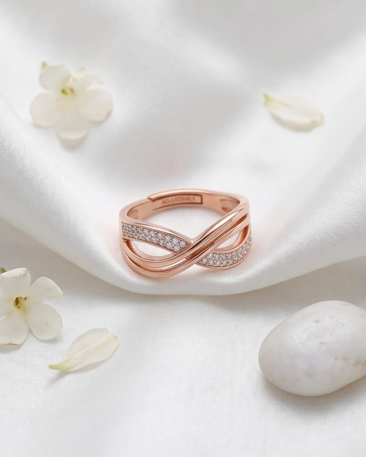 Rose gold ring with diamonds on a white fabric background with flowers and an egg. #color_rose gold