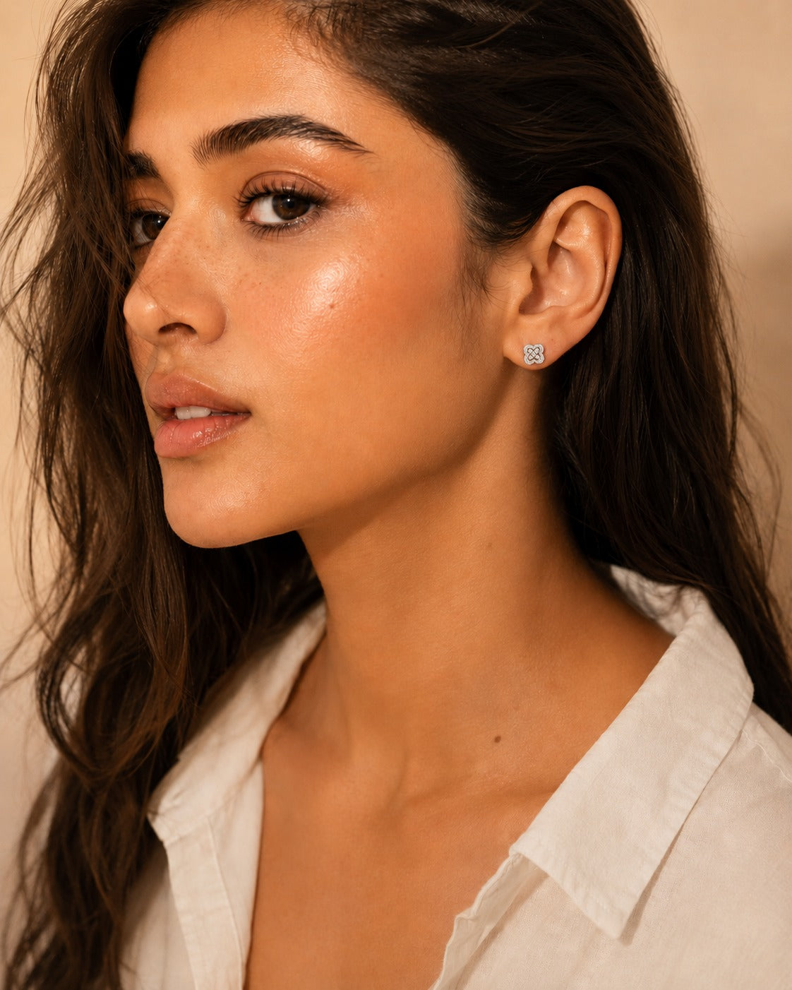 Close-up of a woman wearing a silver earring against a neutral      background #color_silver