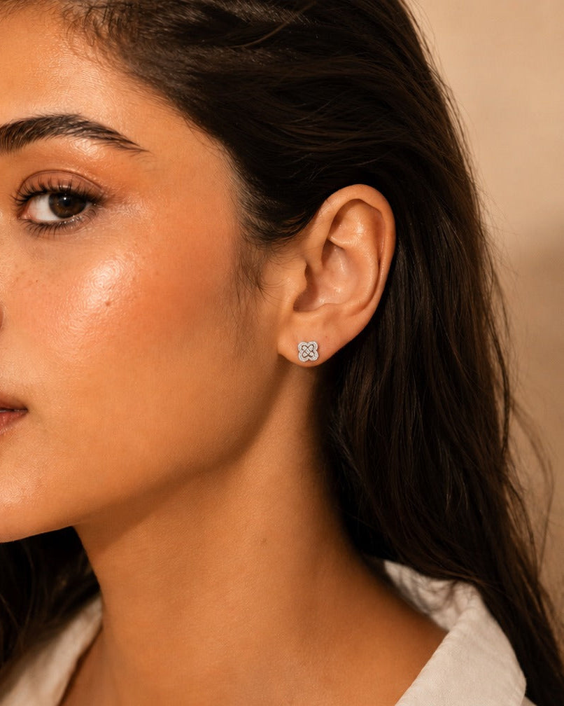 Close-up of a woman wearing a silver earring against a neutral      background #color_silver